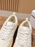 Moncler luxury shoes in cream, close-up front views with lace-up and embossed patch.