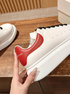 White leather sneakers with red instep panel and black lace-up front