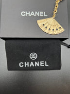 Chanel gold fan charm with chain and clasp over black gift box