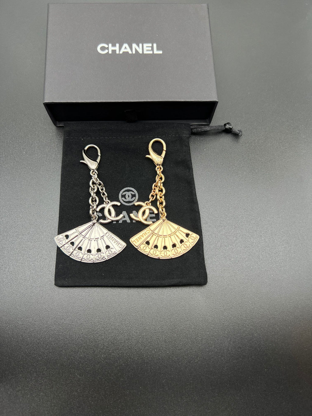 Chanel fan charm set with silver and gold chain links on black pouch