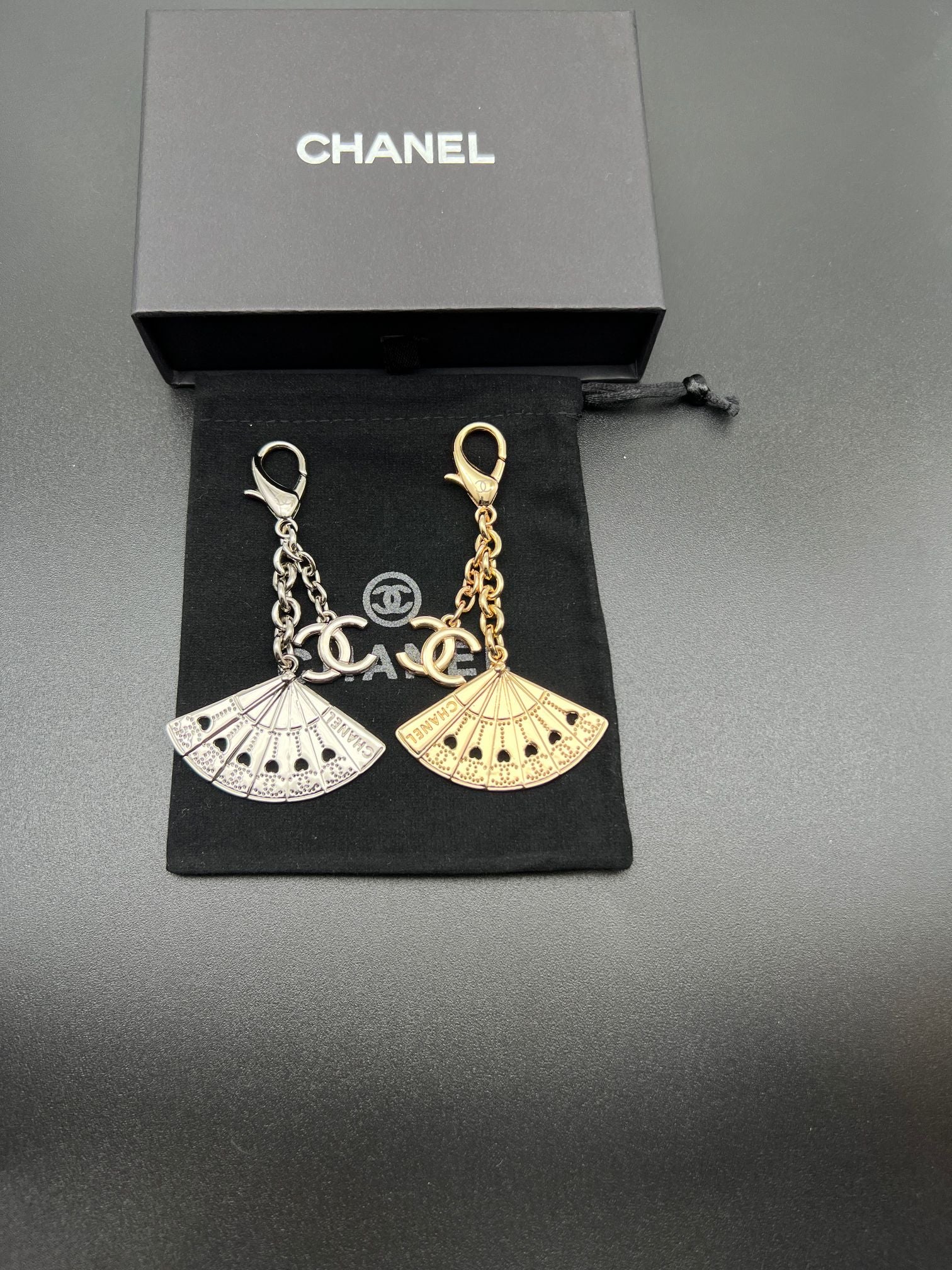 Chanel fan charm set with silver and gold chain links on black pouch