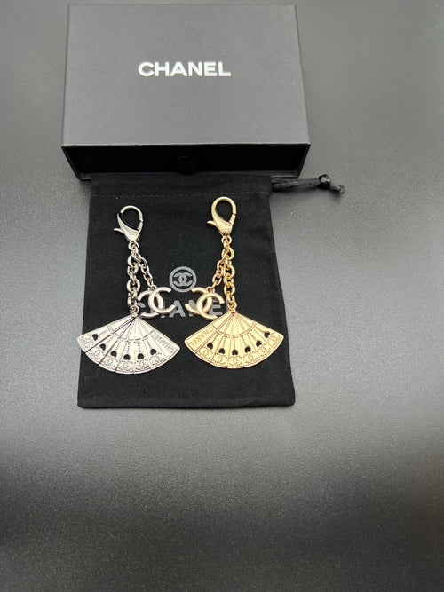 Chanel fan charm set with silver and gold chain links on black pouch