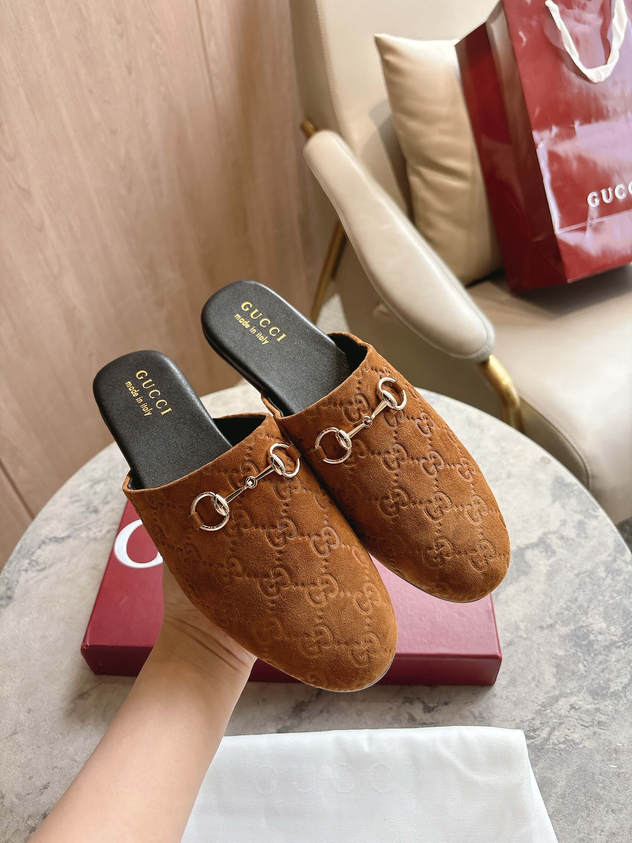 Gucci unisex tan GG mules with gold-tone horsebit, on display with dust bag