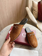 Gucci unisex tan GG mules, gold-tone horsebit, shown with hand