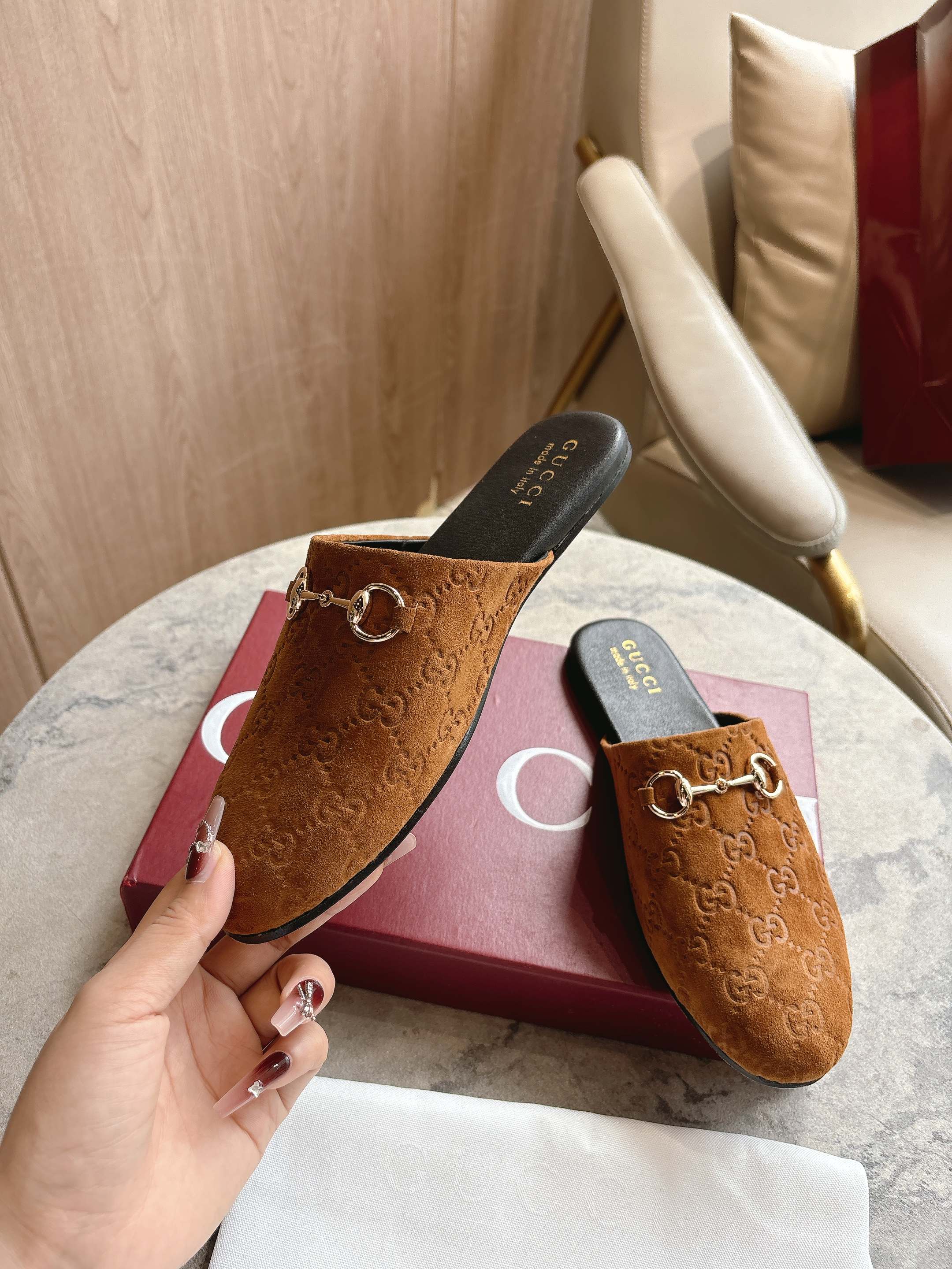 Gucci unisex tan GG mules, gold-tone horsebit, shown with hand