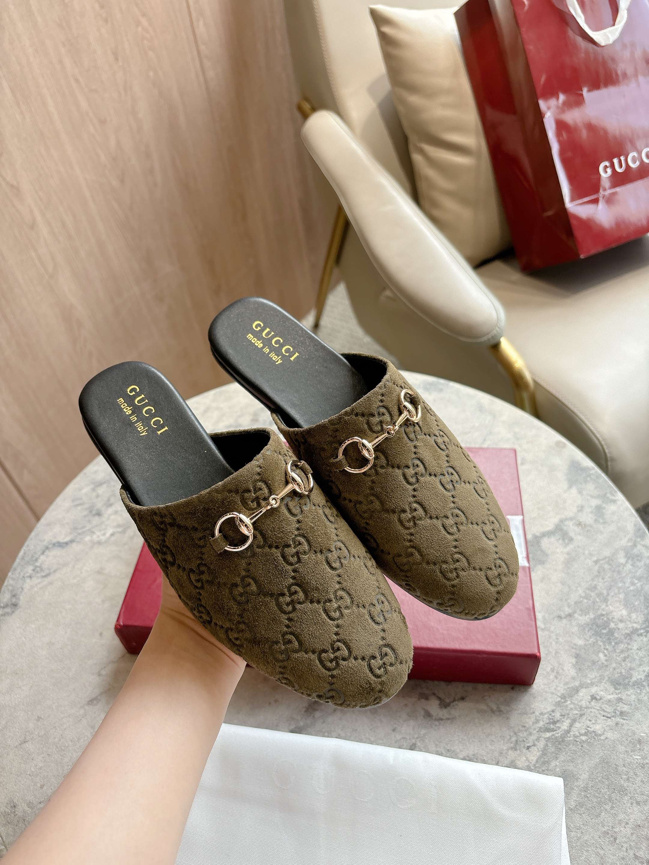 Gucci unisex slide mules with olive-brown GG canvas uppers and gold-tone horsebit detail.