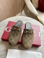 Gucci unisex slide mules in olive-brown GG canvas with gold-tone horsebit detail.