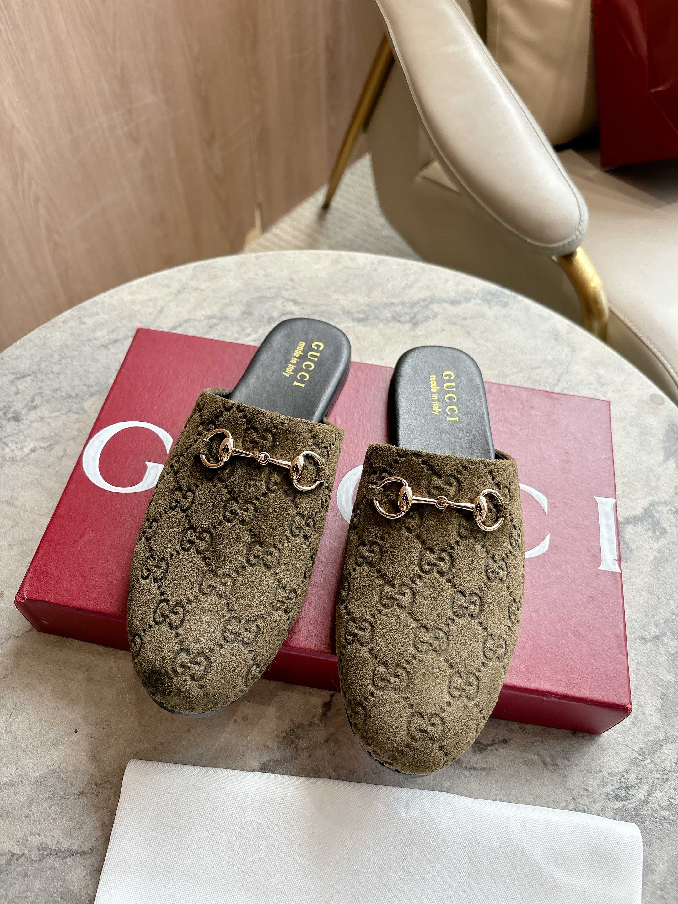 Gucci unisex slide mules in olive-brown GG canvas with gold-tone horsebit detail.