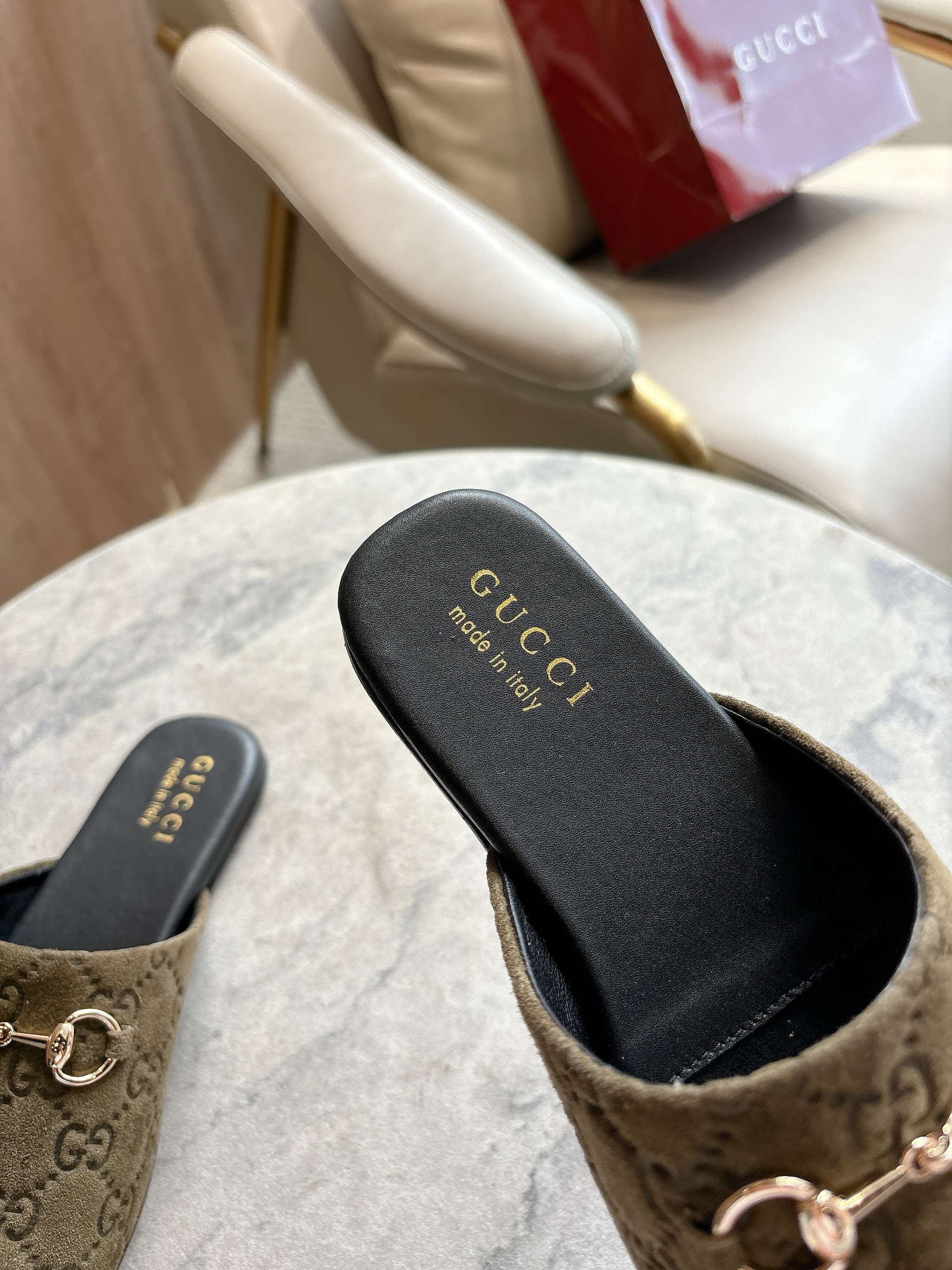 Gucci unisex slide mule showing black footbed with Gucci logo and olive-brown GG strap.