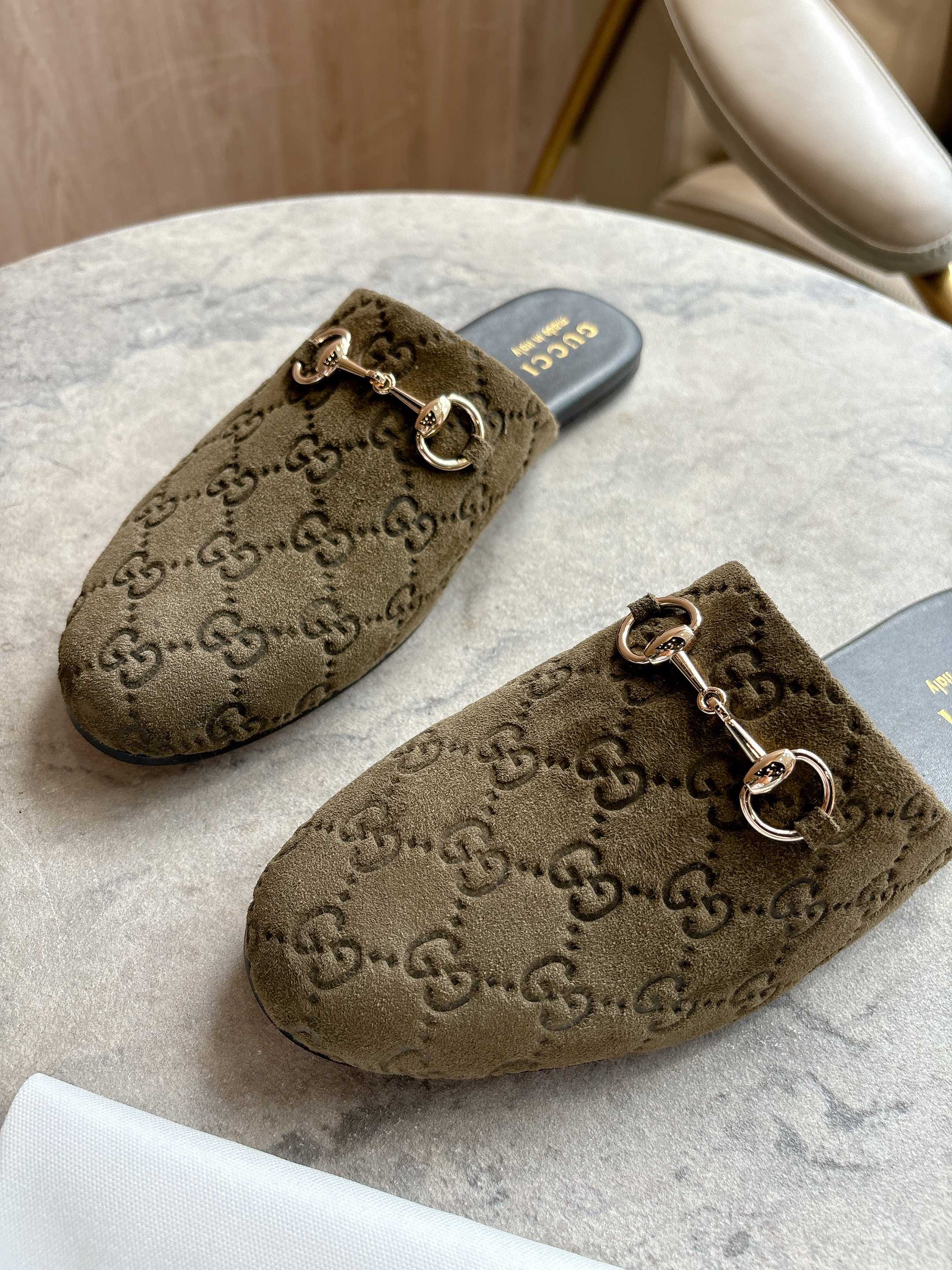 Close view of Gucci unisex slide mules in olive-brown GG canvas with gold-tone horsebit.