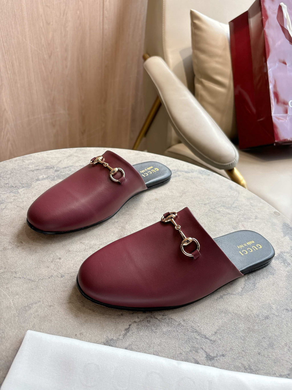 Pair of burgundy leather mule loafers with gold-tone horsebit on dark insoles