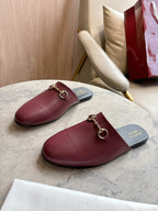 Pair of burgundy leather mule loafers with gold-tone horsebit on dark insoles