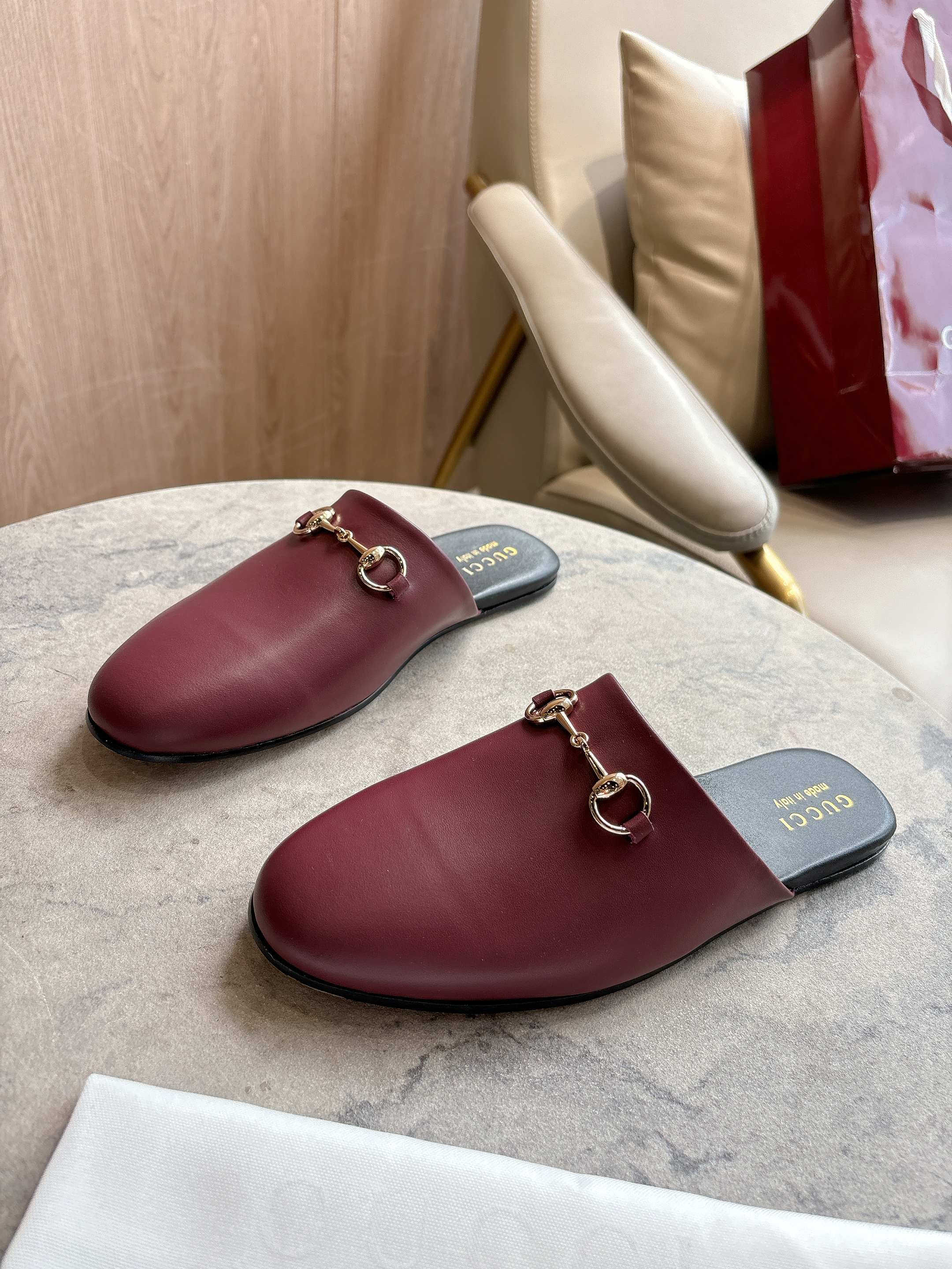 Pair of burgundy leather mule loafers with gold-tone horsebit on dark insoles