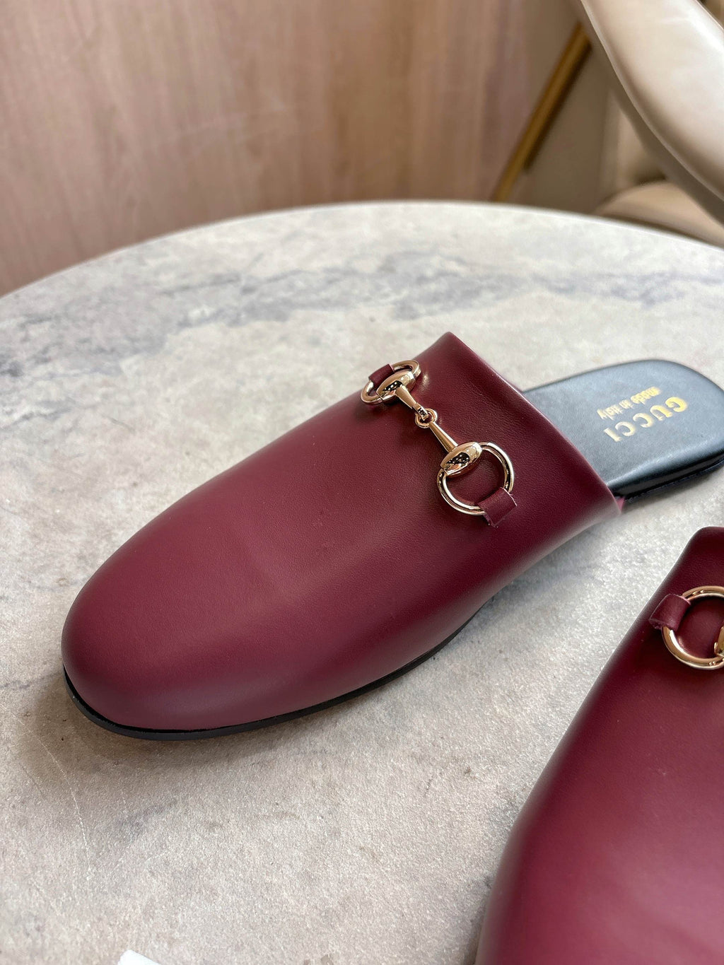Burgundy leather mule with gold-tone horsebit hardware on dark footbed