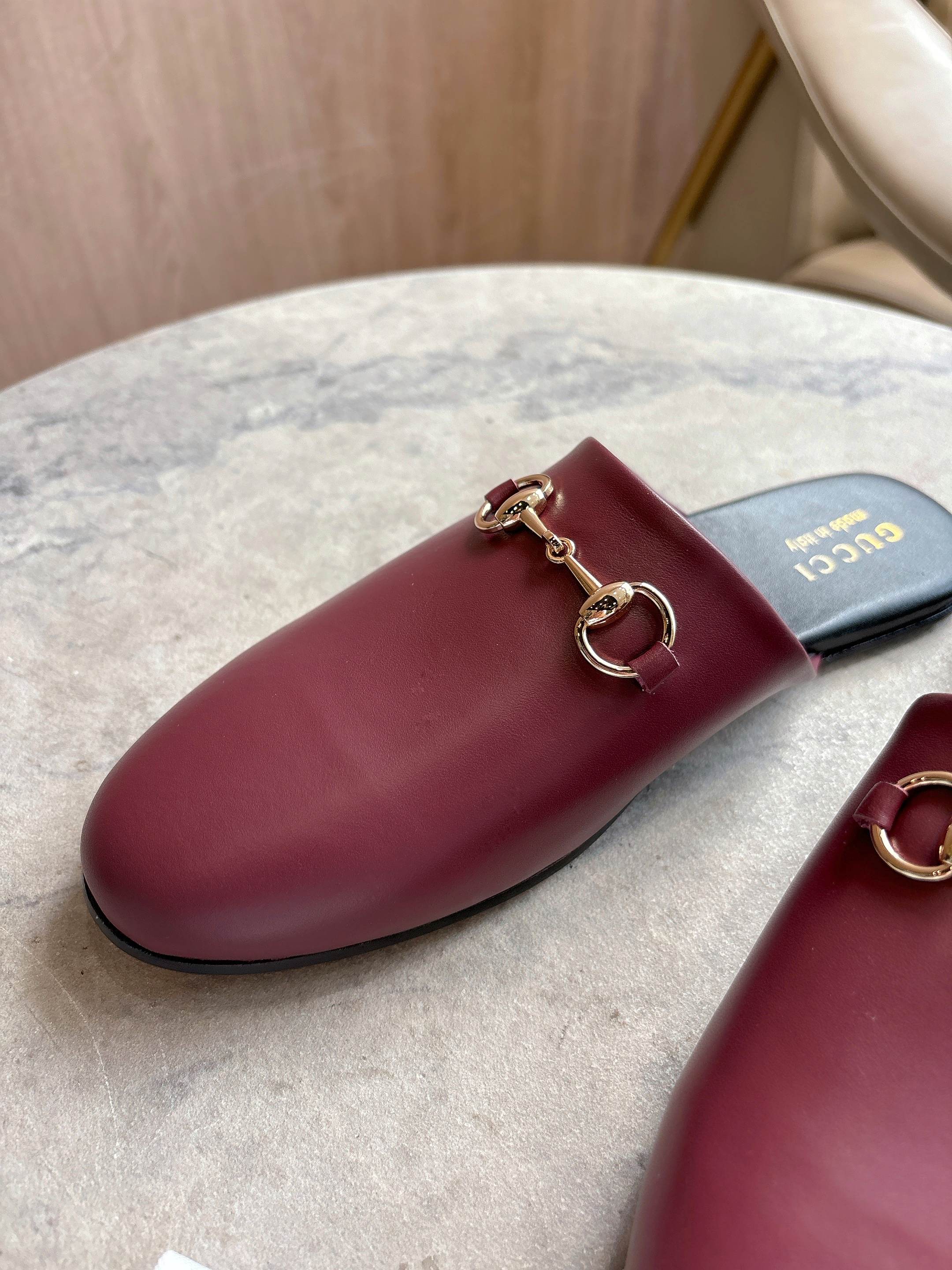 Burgundy leather mule with gold-tone horsebit hardware on dark footbed
