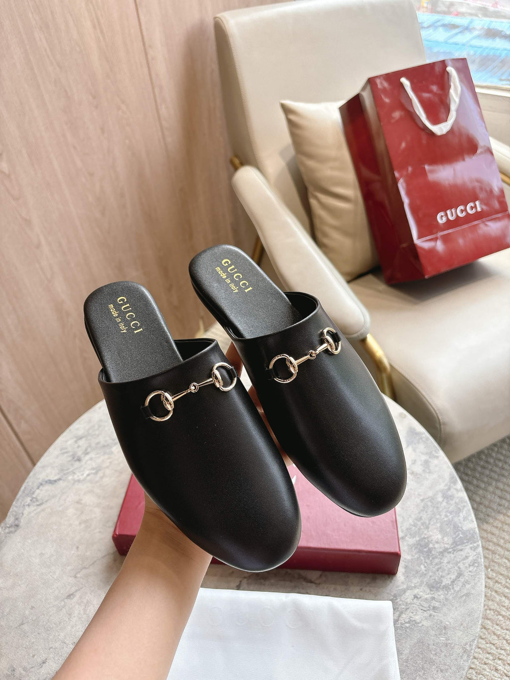 Pair of black unisex loafers with gold chain detail on branded footbeds