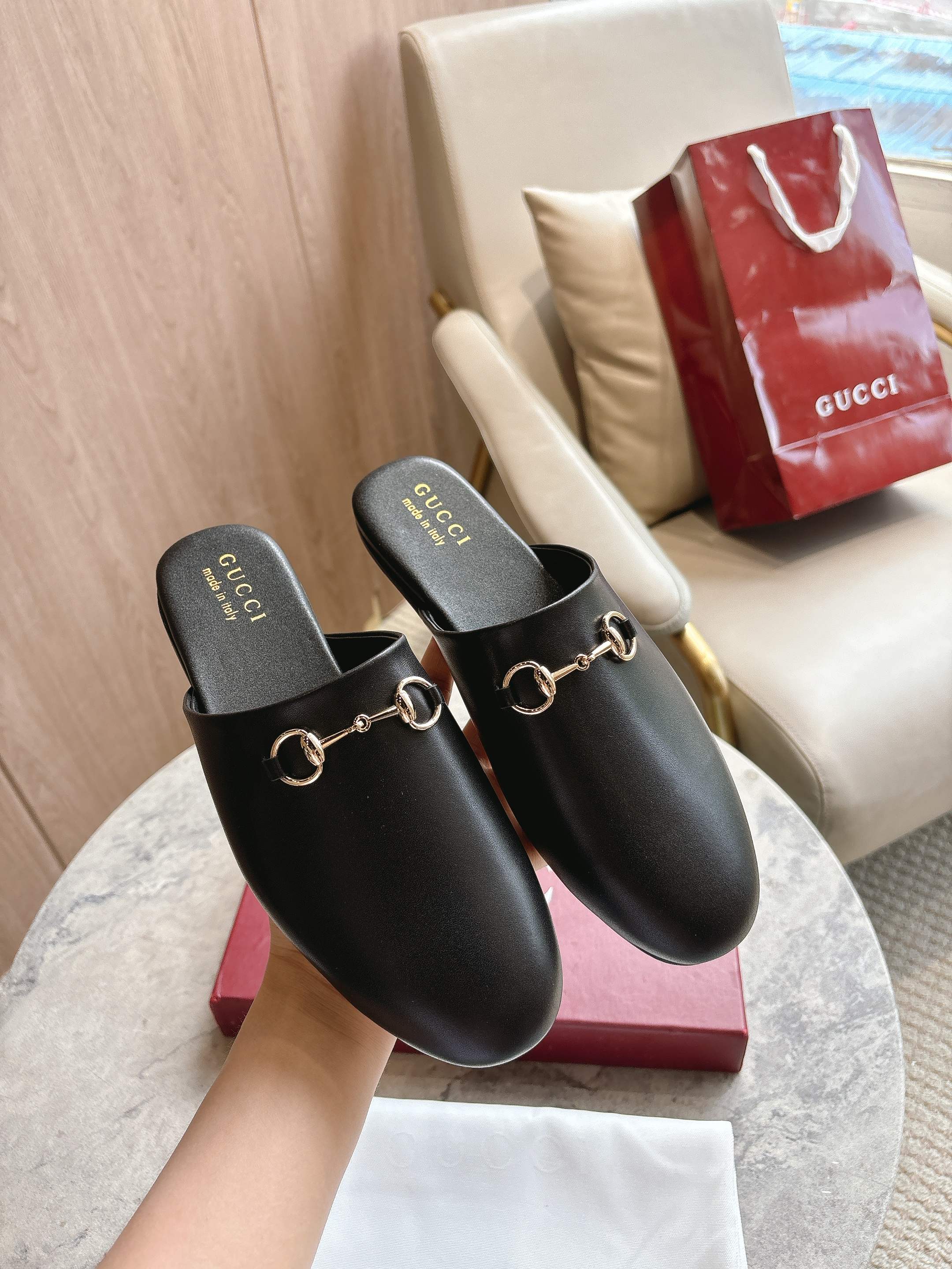 Pair of black unisex loafers with gold chain detail on branded footbeds