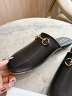 Black unisex loafer with gold chain bar detail, shown close-up