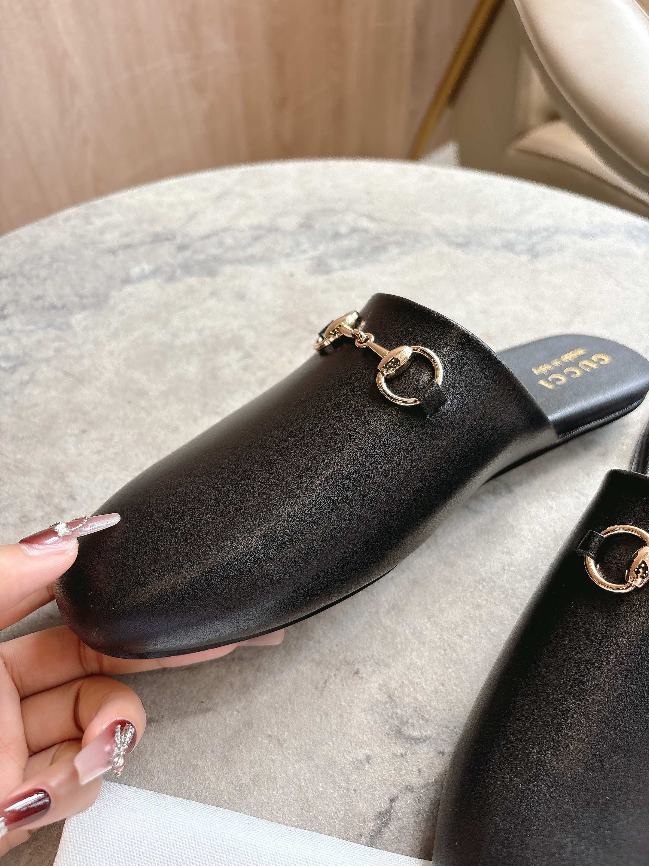 Black unisex loafer with gold chain bar detail, shown close-up