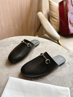 Black unisex loafers with gold chain hardware and branded footbed
