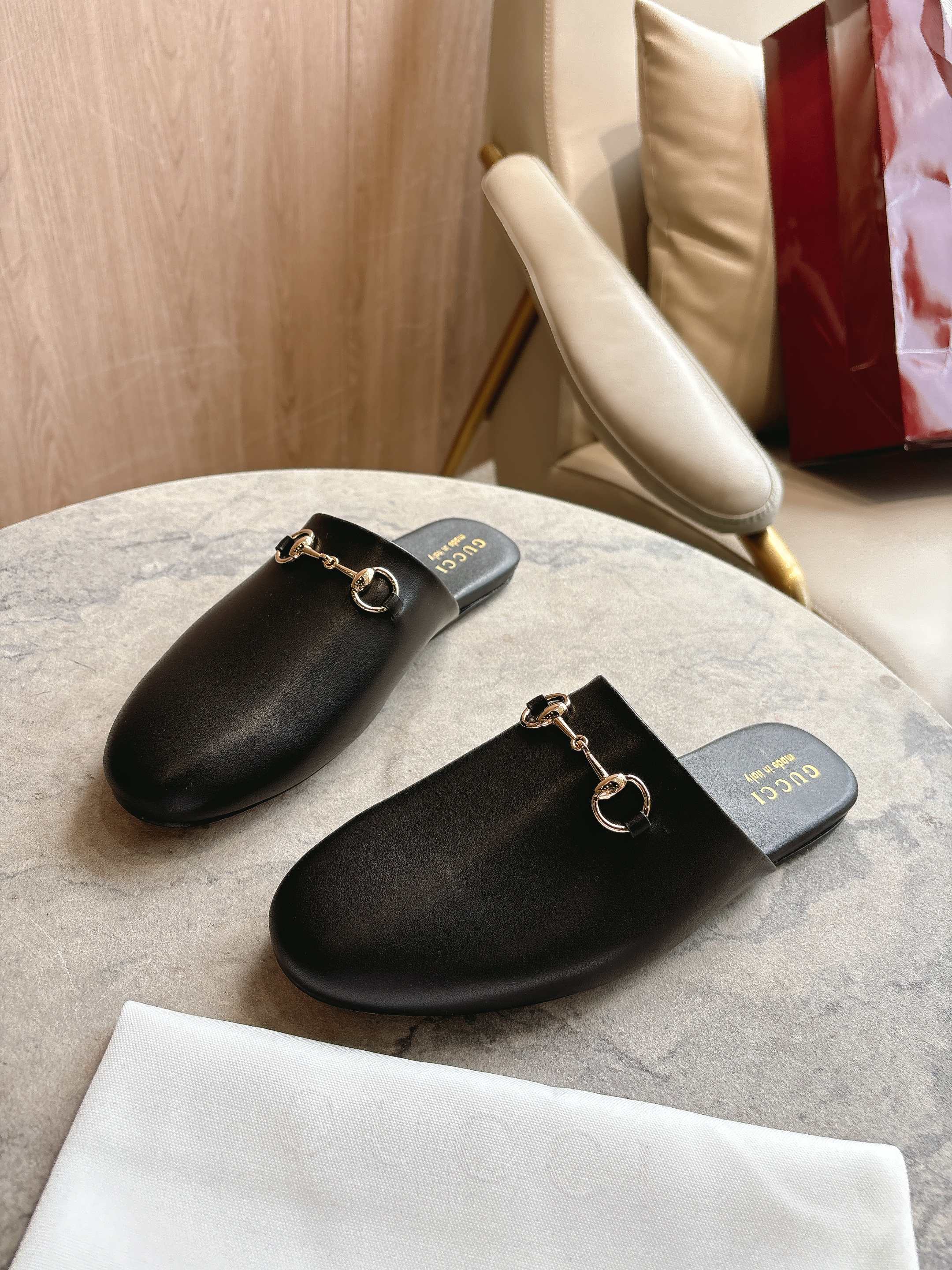 Black unisex loafers with gold chain hardware and branded footbed