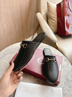 Black unisex loafers with gold chain hardware on branded insoles