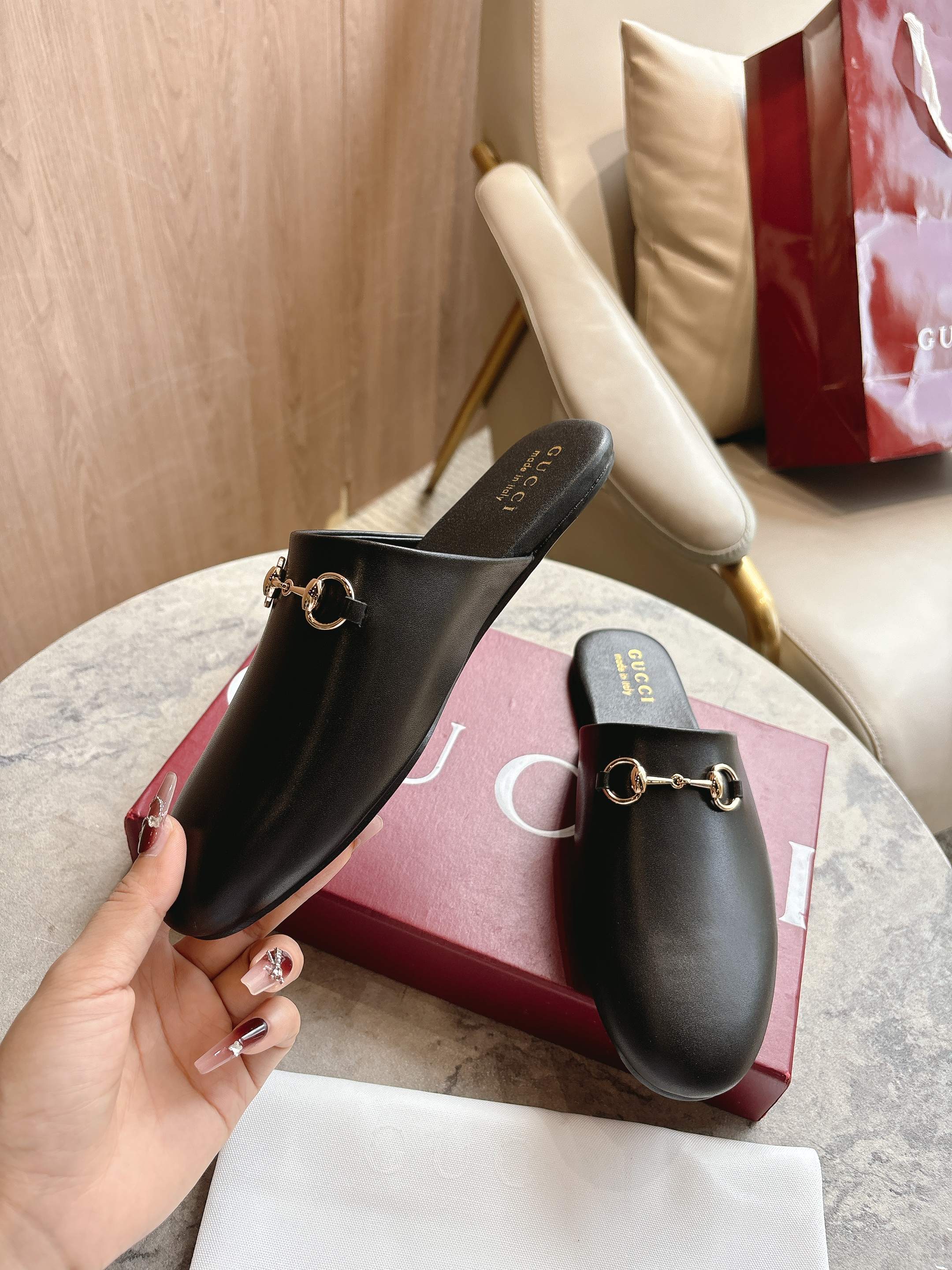 Black unisex loafers with gold chain hardware on branded insoles