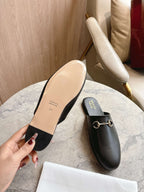 Black unisex loafer with gold chain detail and light beige sole underside