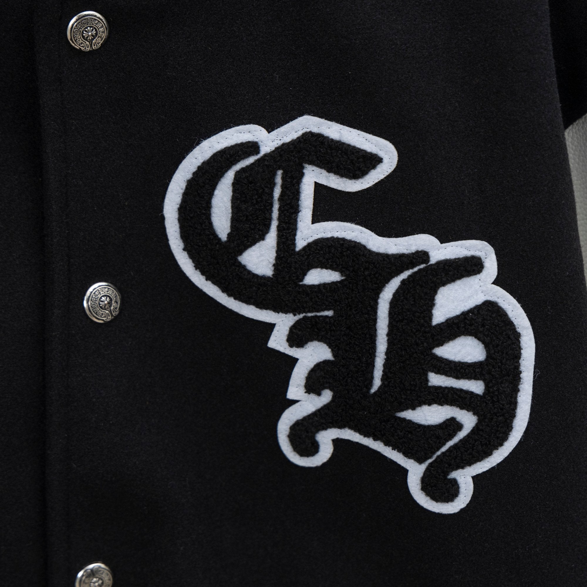 Black varsity jacket close-up with large embroidered emblem on front