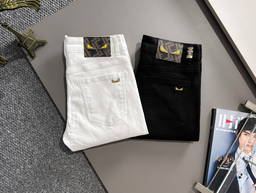 Black and white denim pants folded and displayed, with front pockets and logo patch