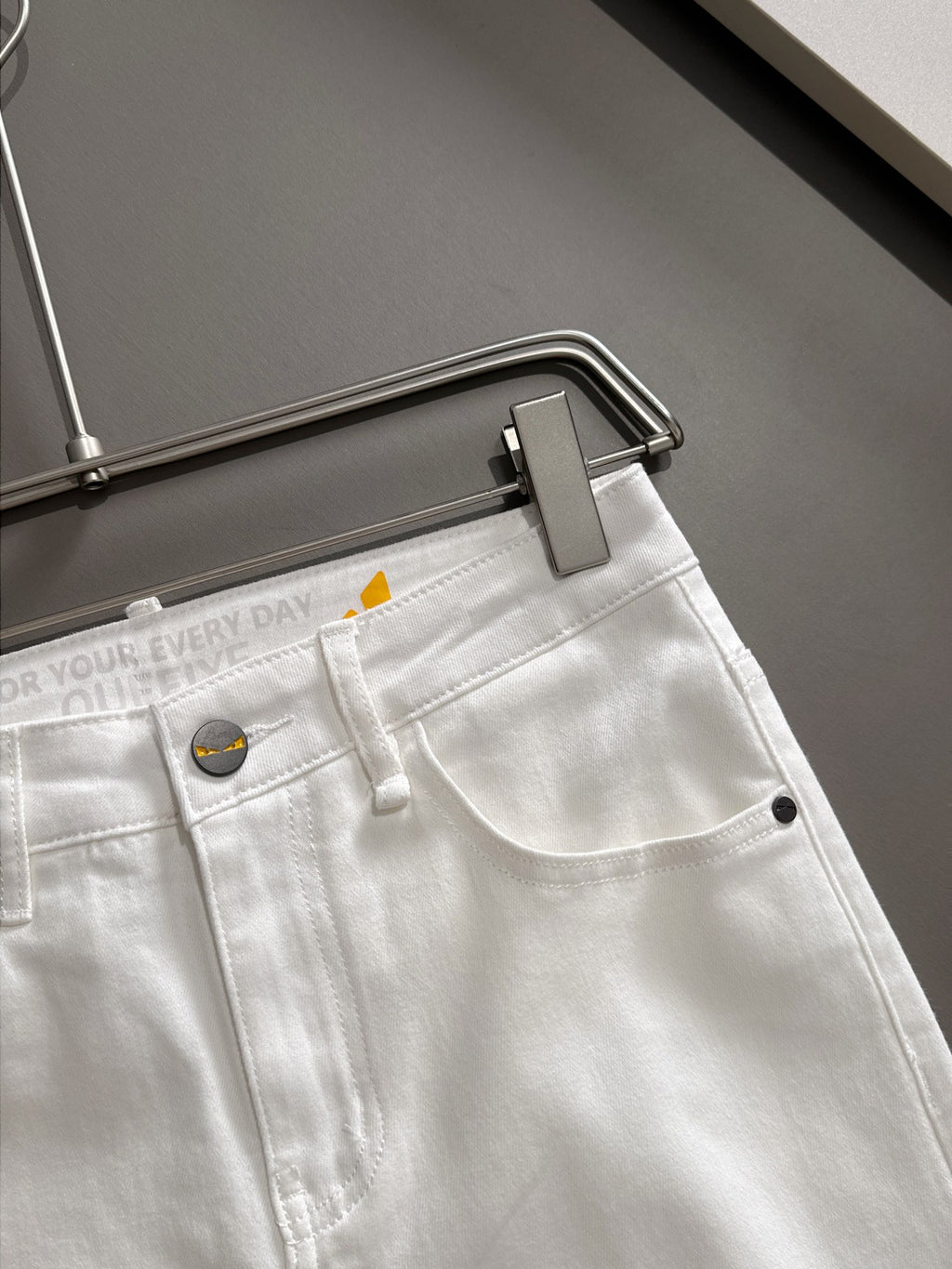White denim pants close-up at waistband, button and belt loop detail