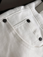 White denim pants close-up of front pocket and black button details