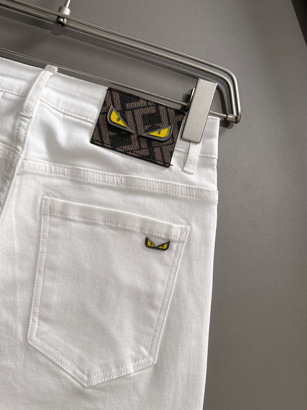 White denim pants close-up of back pocket with stitched seam and hanger
