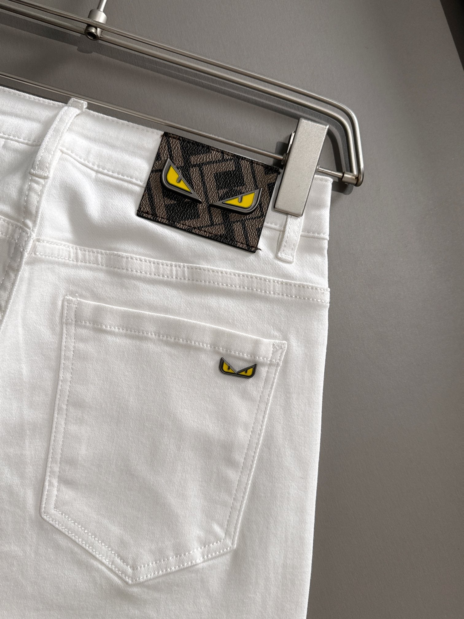 White denim pants close-up of back pocket with stitched seam and hanger