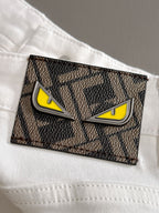 Rectangular logo patch on white denim pocket with yellow eyes and black border