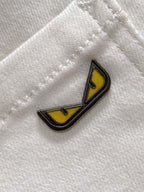 Yellow and black enamel logo patch on white denim fabric