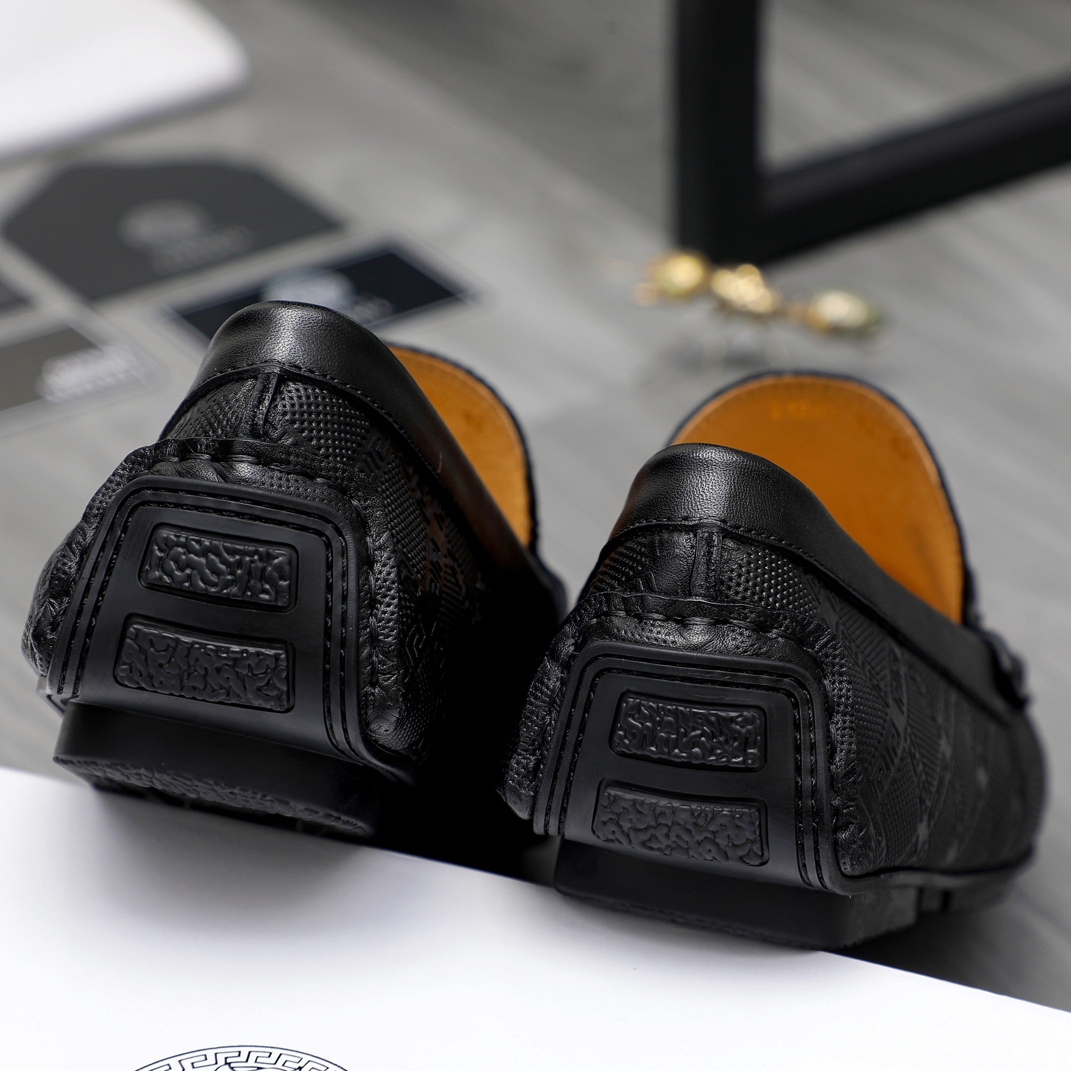 Back view of black leather loafers showing cushioned heel and textured outsole.