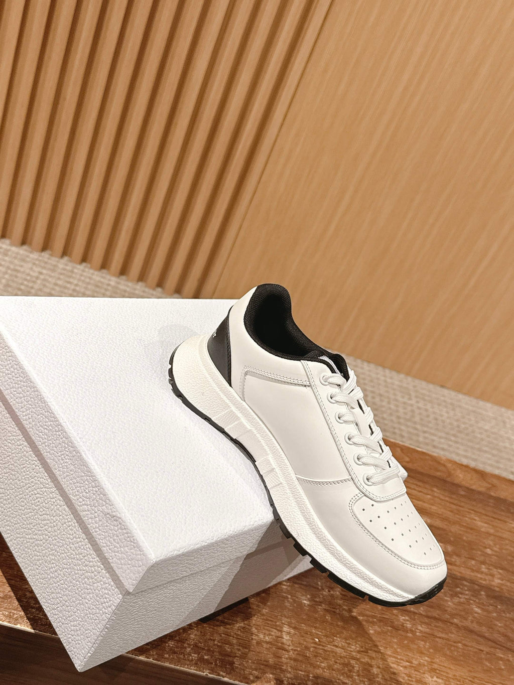 Dior unisex sneakers, white upper with black collar and lace-up front, angled view