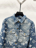 Blue denim jacket front with white monogram pattern, flap pockets and gold buttons