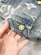 Blue denim jacket cuff with white monogram stitching and round gold logo patch