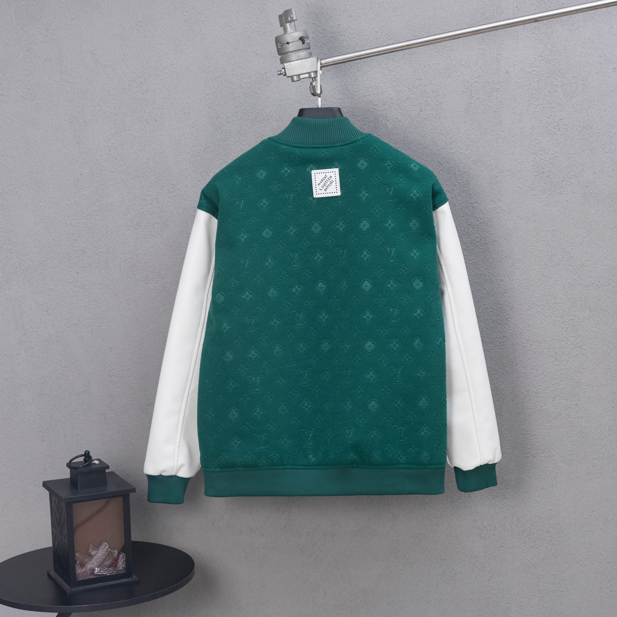 Long-sleeve varsity jacket back, dark green with ribbed hem and white sleeve panels.