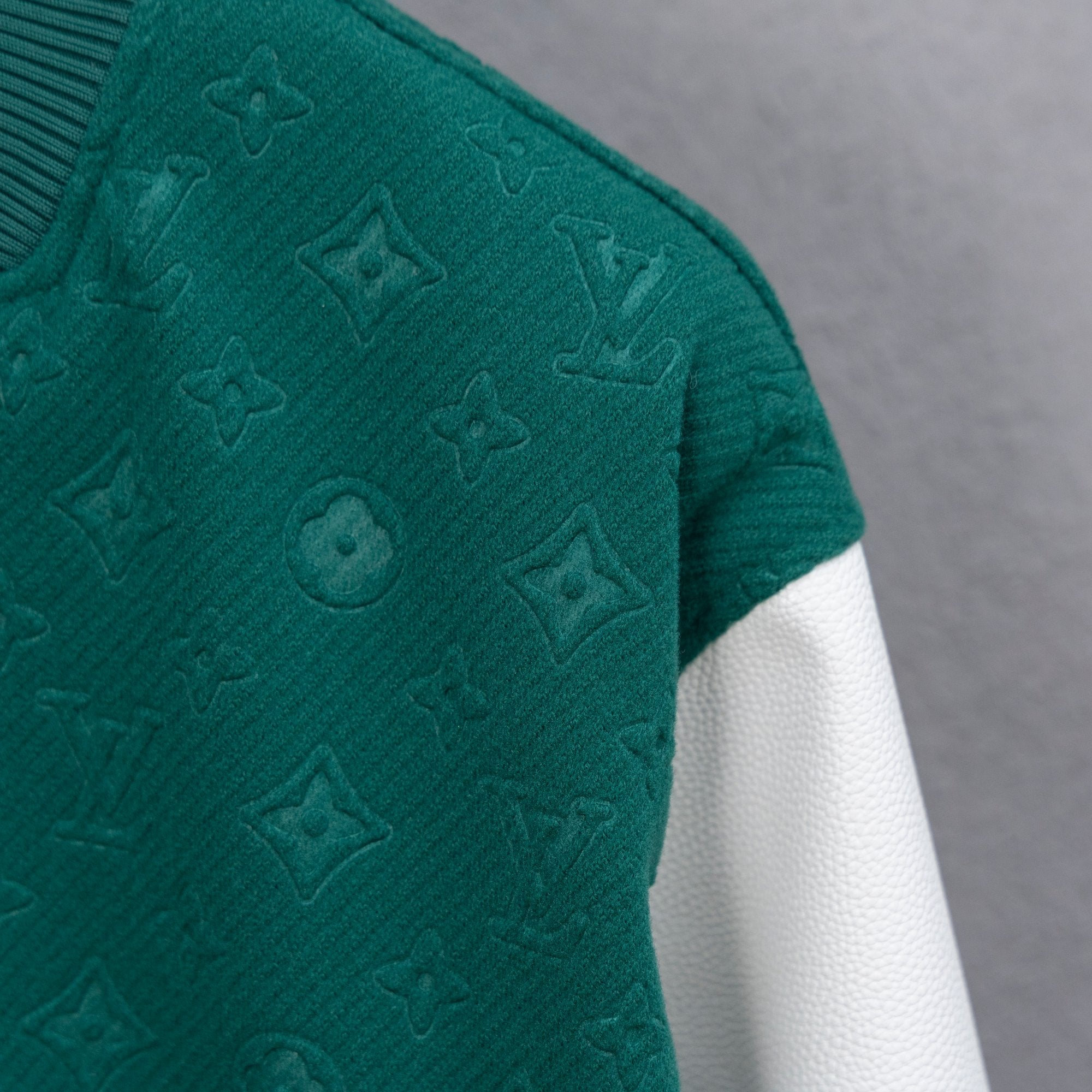 Long-sleeve jacket shoulder with embossed monogram pattern and white sleeve trim.