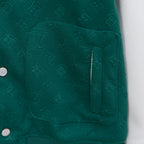 Jacket chest pocket with embossed monogram texture and seam stitching near snap buttons.