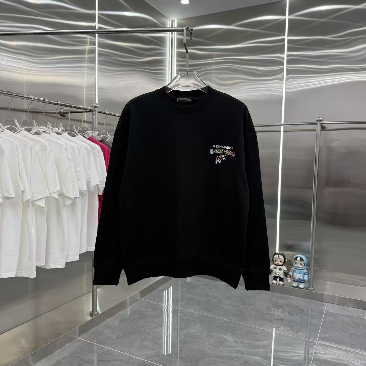 Black long-sleeve crewneck sweatshirt, small multicolor chest graphic.
