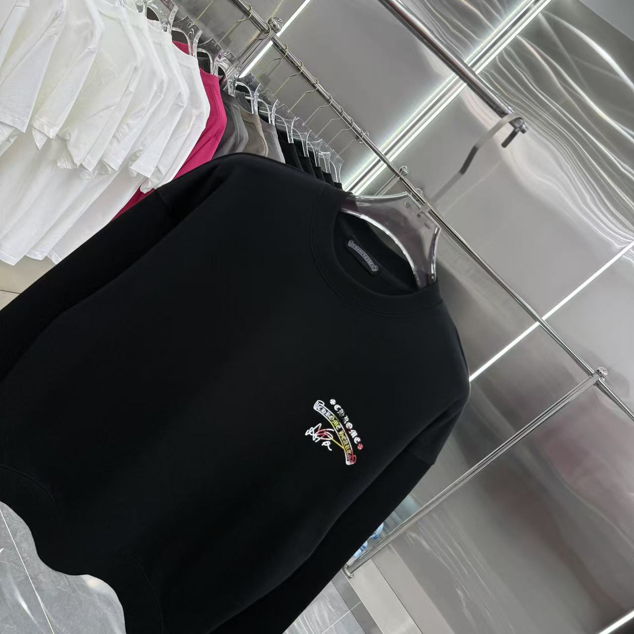 Black long-sleeve crewneck sweatshirt, chest logo with multicolor details.