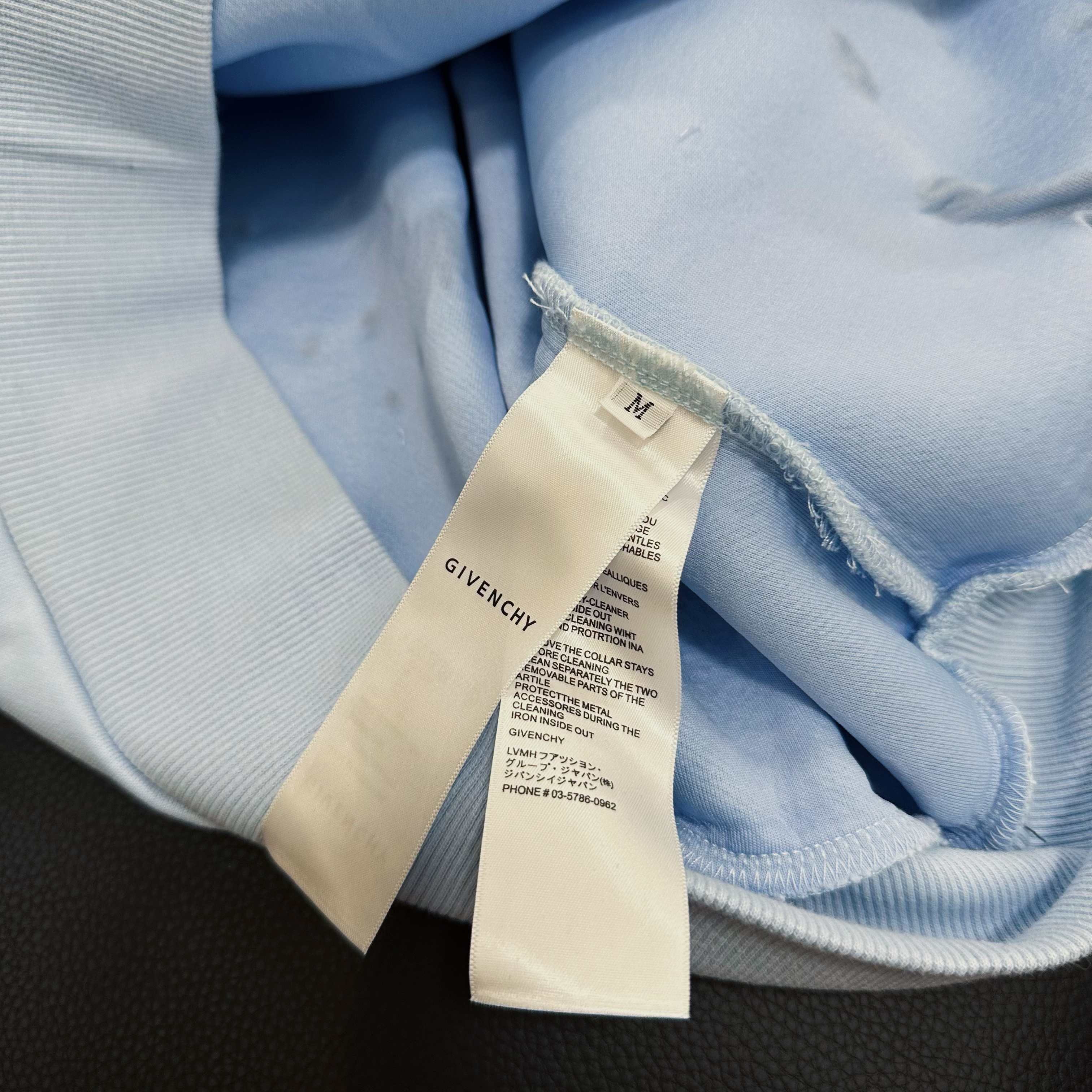 Light blue hoodie care label on inside neck with drawstring cord