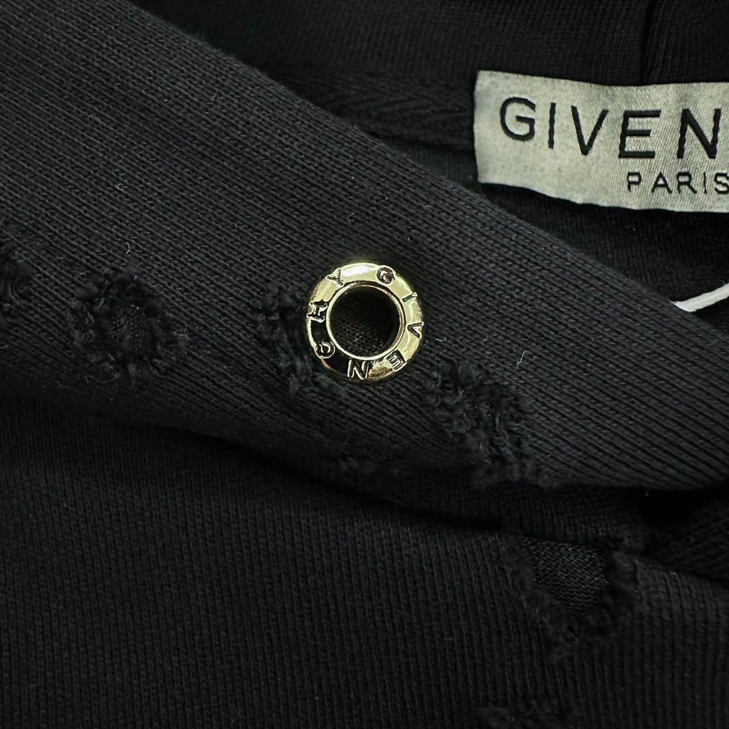 Black hoodie cuff detail with gold snap button and partial Givenchy Paris label
