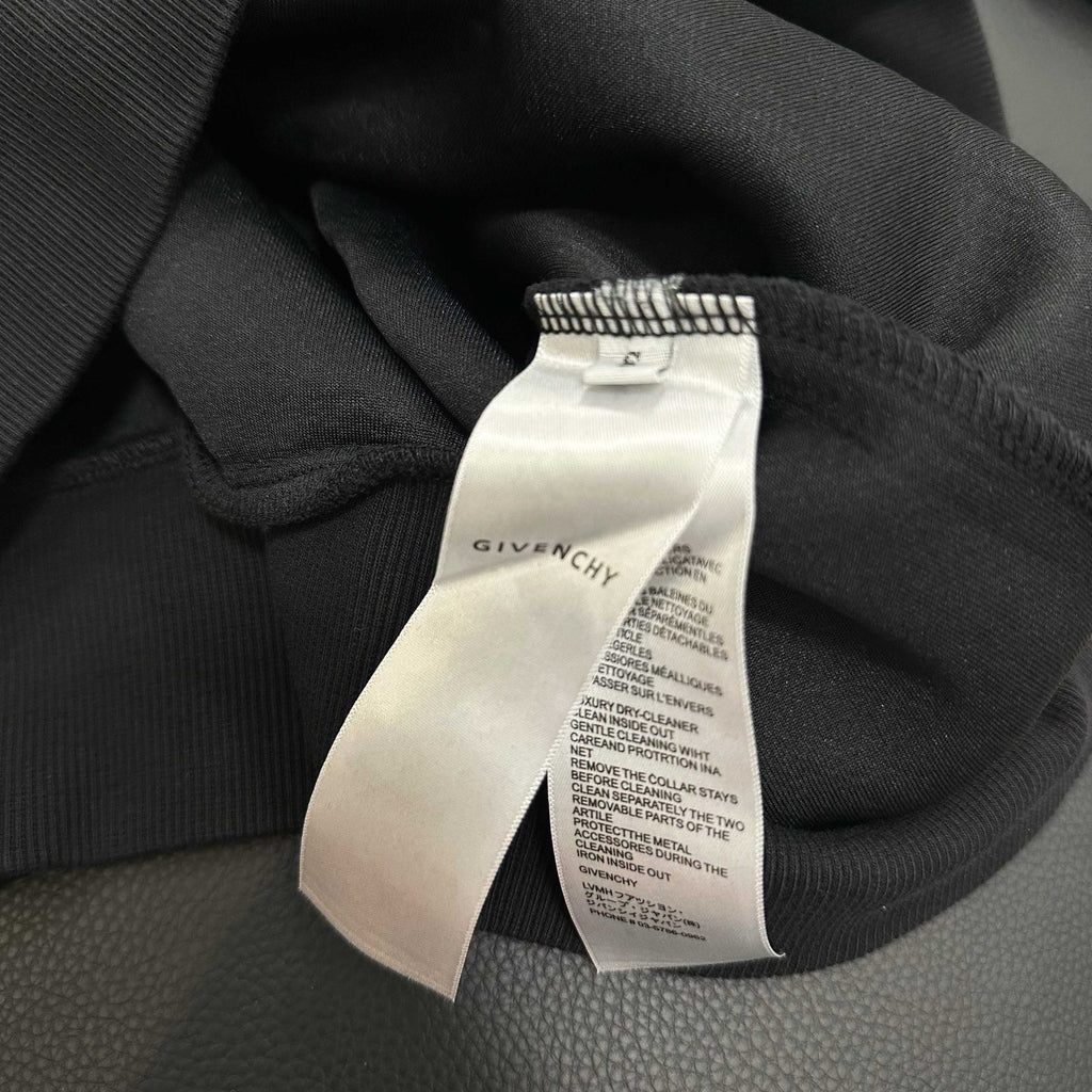 Black hoodie with white care label tag attached at collar
