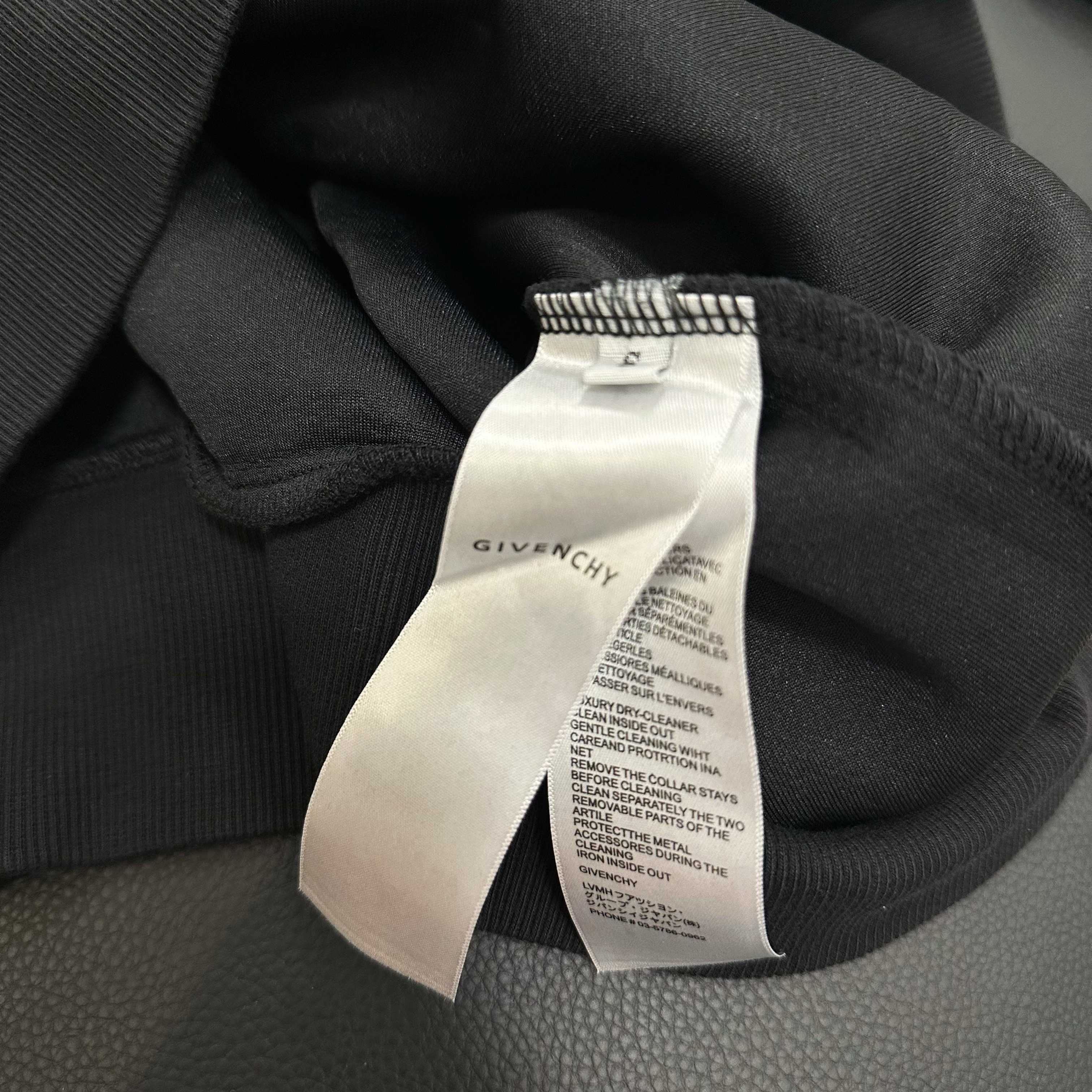 Black hoodie with white care label tag attached at collar