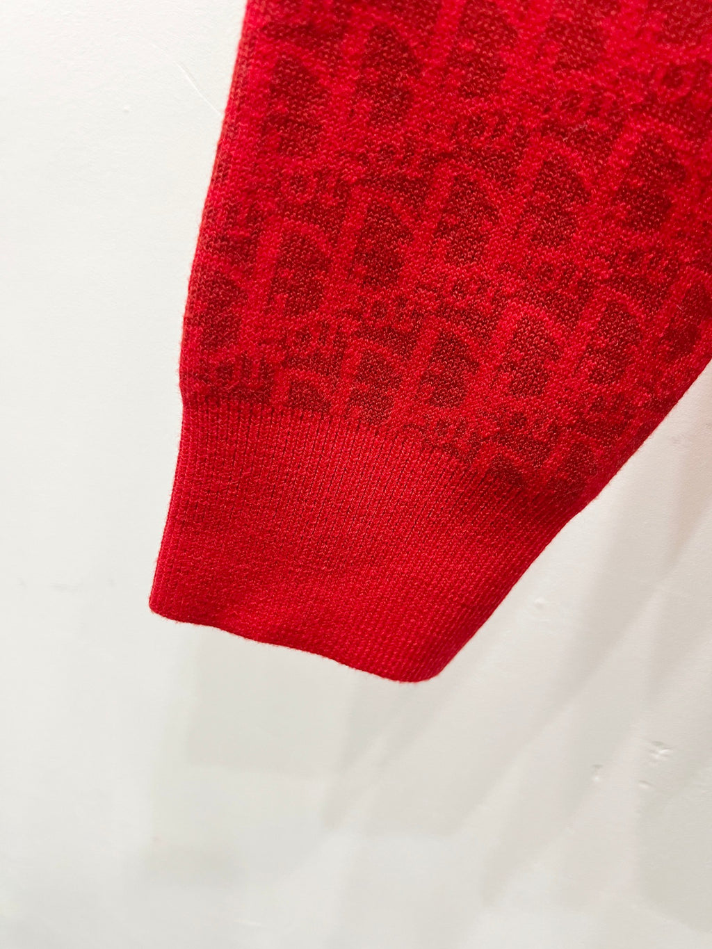 Red zip-front hooded sweatshirt lower sleeve and hem close-up, jacquard knit texture